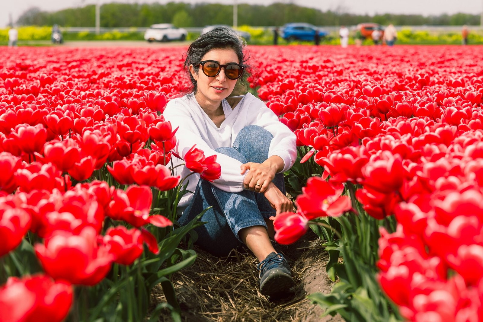 a woman sitting in a field of red tulips